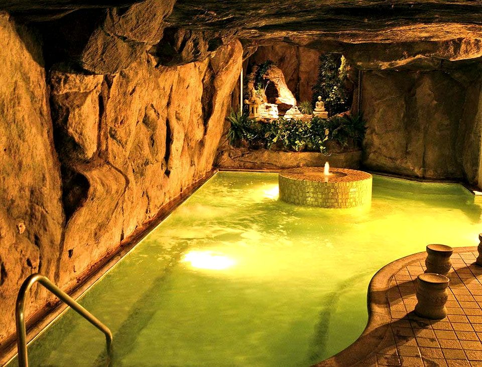 The figure-eight mineral pool inside the stone grotto, with the fountain at its center